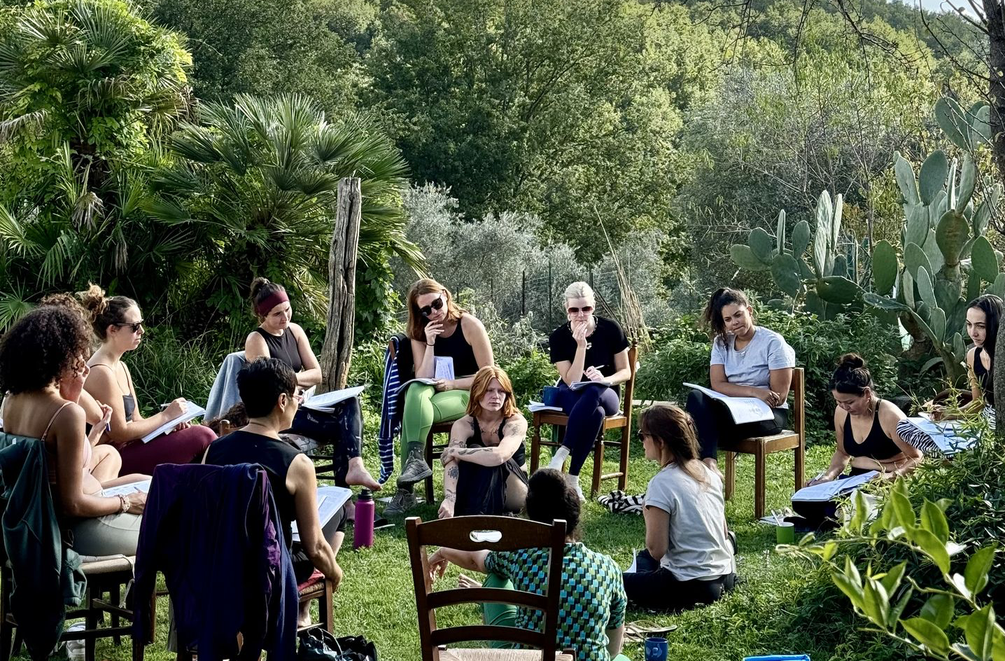 Group learning session on yoga history and alignment Students studying yoga philosophy and anatomy in an outdoor natural setting